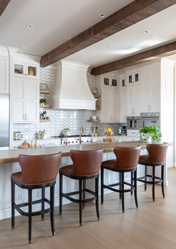 Inspiration for a transitional u-shaped kitchen in Dallas with recessed-panel cabinets, white cabinets, wood benchtops, stainless steel appliances, medium hardwood floors, with island, brown floor, brown benchtop and exposed beam.