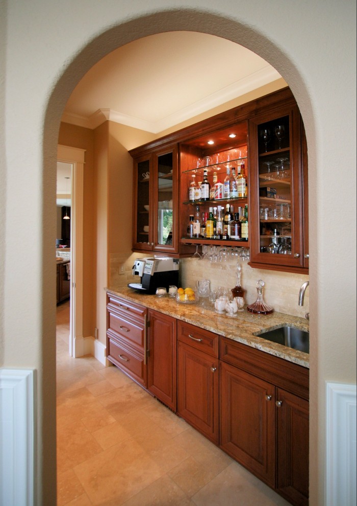 Expansive traditional u-shaped home bar in Portland with an undermount sink, raised-panel cabinets, medium wood cabinets, granite benchtops, yellow splashback, stone tile splashback, yellow floor, yellow benchtop and travertine floors.