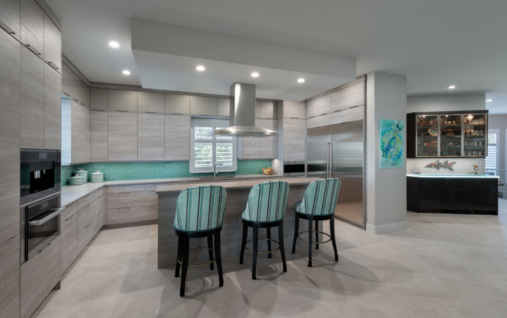 Inspiration for a mid-sized modern u-shaped kitchen in Tampa with an undermount sink, flat-panel cabinets, grey cabinets, quartz benchtops, green splashback, glass tile splashback, stainless steel appliances, porcelain floors, with island, grey floor and grey benchtop.