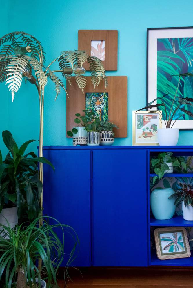 This is an example of a mid-sized tropical enclosed living room in San Diego with blue walls, medium hardwood floors, a wall-mounted tv, panelled walls and red floor.