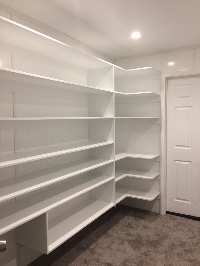 Design ideas for a mid-sized transitional gender-neutral walk-in wardrobe in Raleigh with open cabinets, white cabinets, carpet and brown floor.