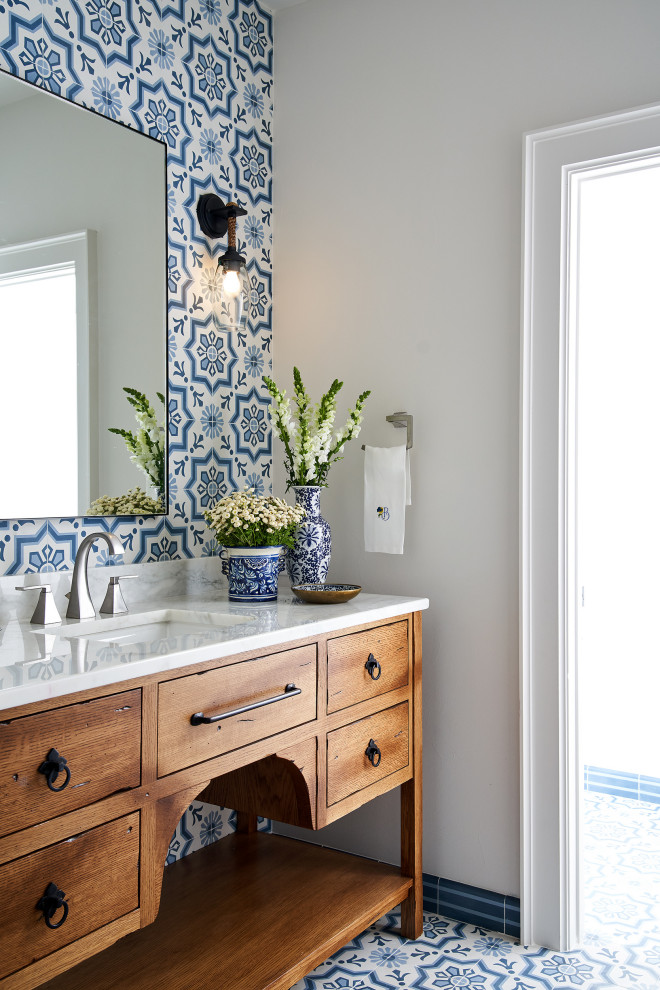 Mediterranes Badezimmer mit blauen Fliesen, weißer Wandfarbe, Quarzit-Waschtisch, blauem Boden, Einzelwaschbecken, freistehendem Waschtisch, hellbraunen Holzschränken, Zementfliesen und Zementfliesen für Boden in Austin