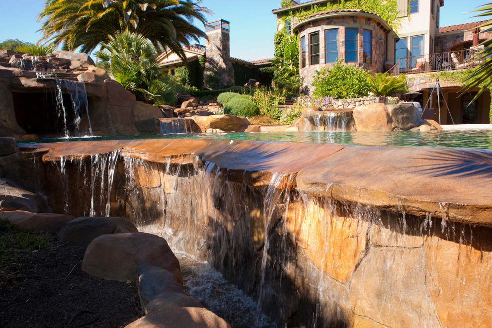 Design ideas for a large mediterranean backyard custom-shaped natural pool in San Francisco with a water feature and natural stone pavers.