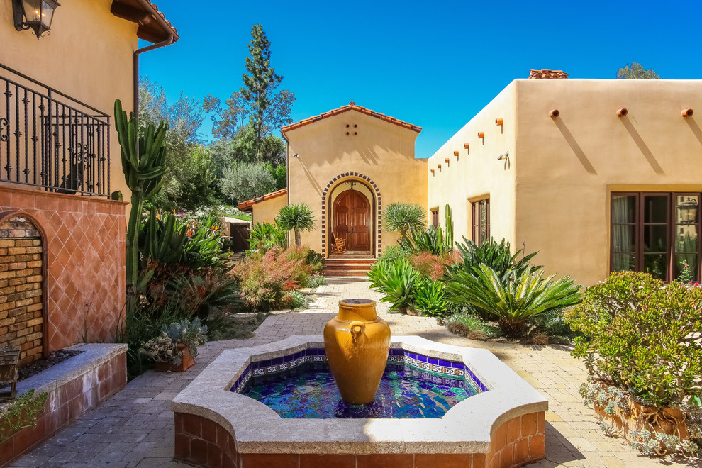 Inspiration for a mediterranean partial sun garden in San Diego with a water feature and concrete pavers.