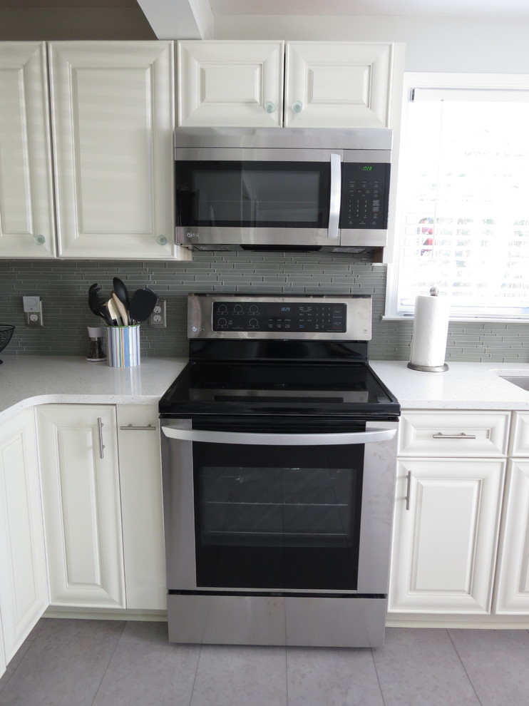 Inspiration for a mid-sized transitional l-shaped purple floor eat-in kitchen remodel with an undermount sink, raised-panel cabinets, white cabinets, quartz countertops, gray backsplash, glass tile backsplash, stainless steel appliances, no island and white countertops