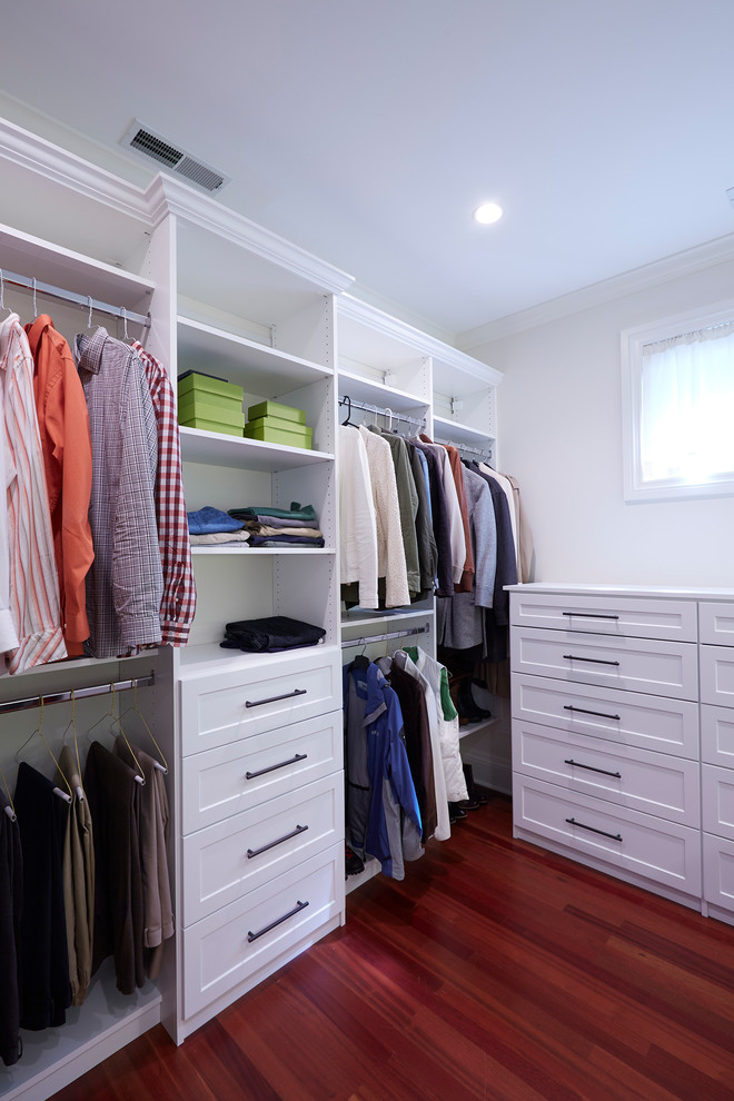 This is an example of a large arts and crafts gender-neutral walk-in wardrobe in Chicago with shaker cabinets, white cabinets, dark hardwood floors and red floor.