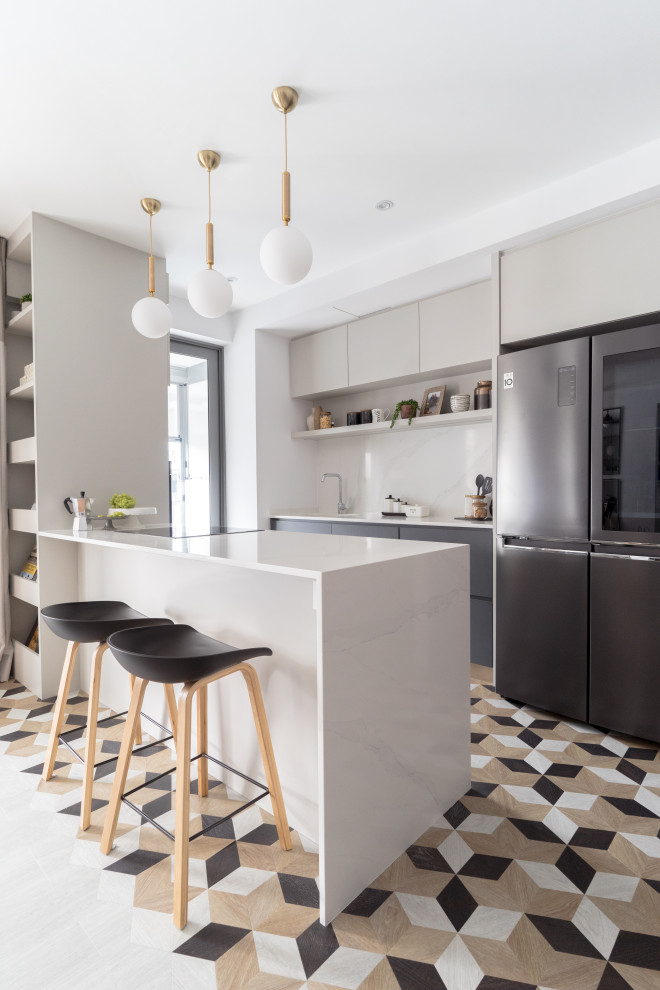 Photo of a contemporary galley kitchen in Singapore with flat-panel cabinets, grey cabinets, black appliances, a peninsula, multi-coloured floor and white benchtop.
