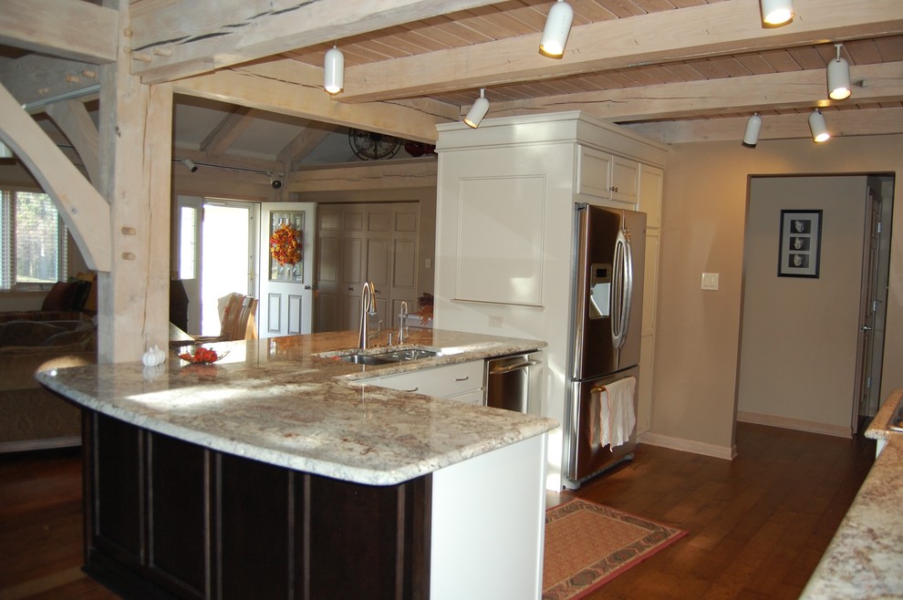 Inspiration for a mid-sized transitional u-shaped medium tone wood floor open concept kitchen remodel in Chicago with an undermount sink, flat-panel cabinets, dark wood cabinets, granite countertops, beige backsplash, stone tile backsplash, stainless steel appliances and a peninsula