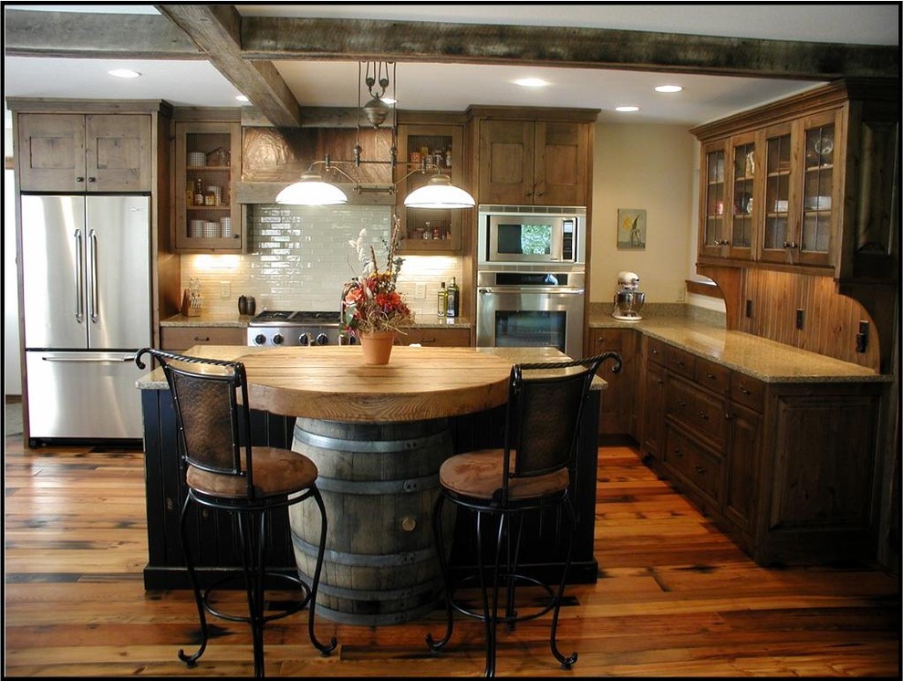 Example of a mountain style medium tone wood floor kitchen design with recessed-panel cabinets, medium tone wood cabinets, granite countertops, beige backsplash, ceramic backsplash, stainless steel appliances, beige walls and an island