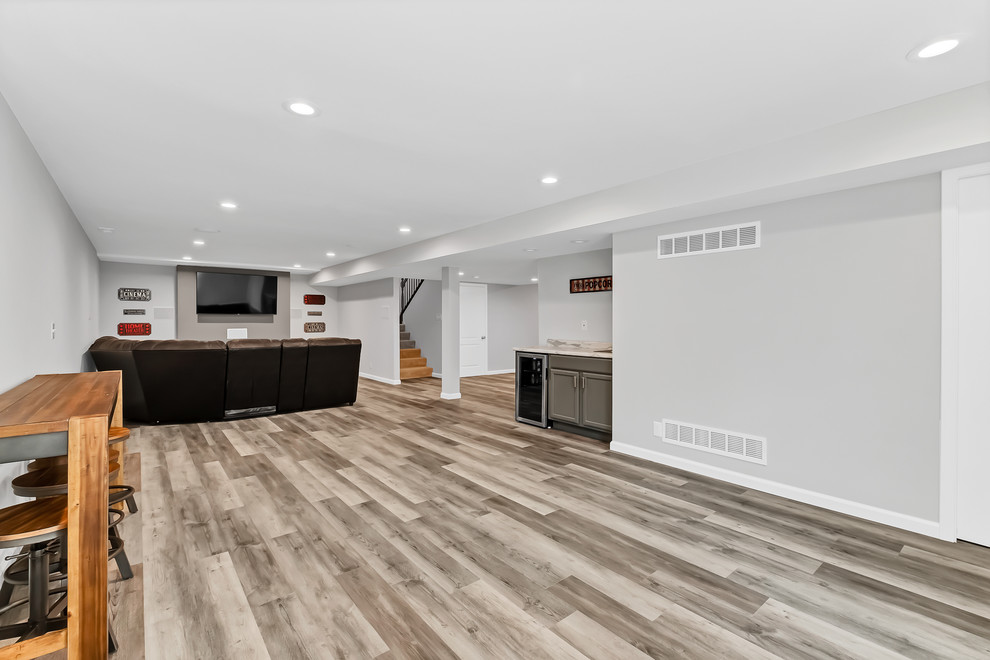 This is an example of a mid-sized modern fully buried basement in St Louis with grey walls, vinyl floors, a standard fireplace and grey floor.