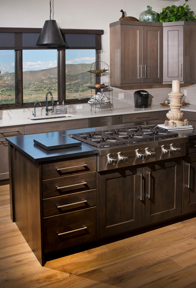 Example of a large transitional u-shaped medium tone wood floor eat-in kitchen design in Denver with an undermount sink, recessed-panel cabinets, gray cabinets, quartz countertops, white backsplash, ceramic backsplash, stainless steel appliances and two islands