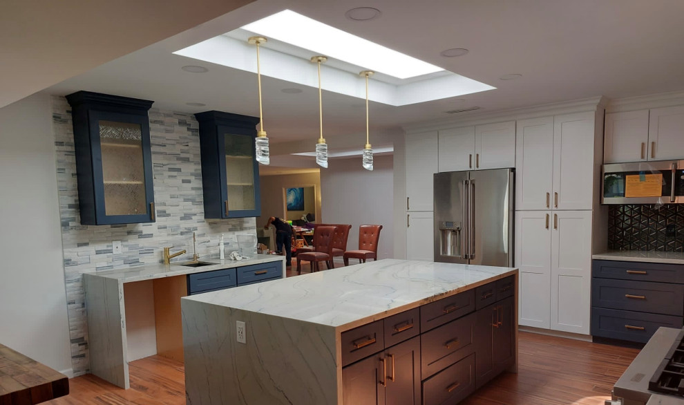 Mid-sized mid-century modern l-shaped dark wood floor and brown floor eat-in kitchen photo in Phoenix with an undermount sink, shaker cabinets, brown cabinets, quartzite countertops, beige backsplash, stone tile backsplash, stainless steel appliances, an island and beige countertops