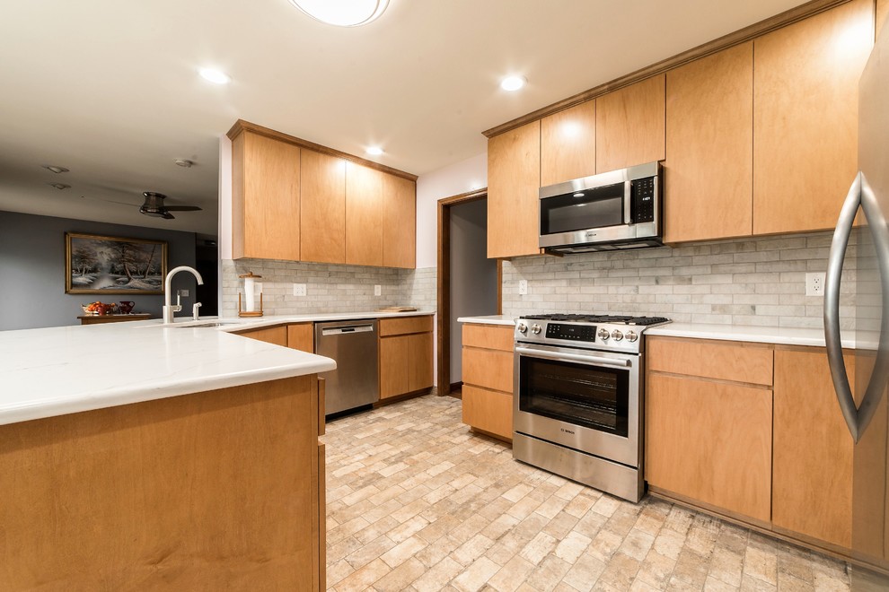 Inspiration for a mid-sized transitional l-shaped ceramic tile and multicolored floor eat-in kitchen remodel in Chicago with an undermount sink, flat-panel cabinets, light wood cabinets, quartz countertops, multicolored backsplash, ceramic backsplash, stainless steel appliances, a peninsula and multicolored countertops