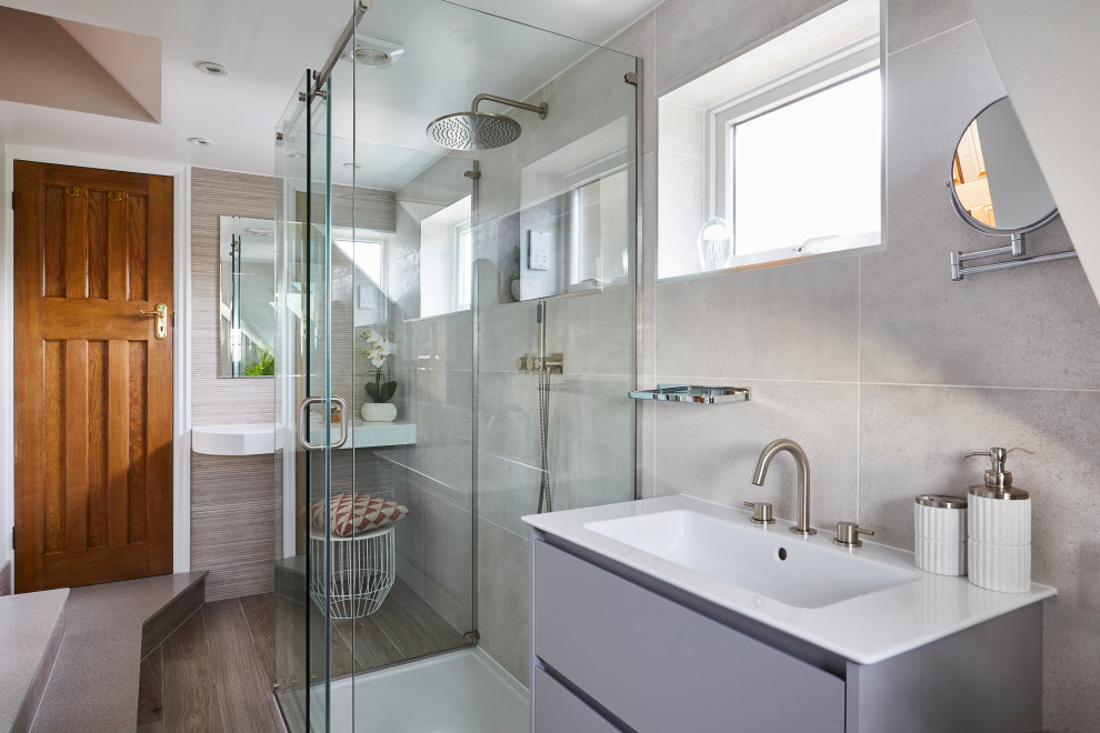 Inspiration for a mid-sized contemporary 3/4 bathroom in London with flat-panel cabinets, grey cabinets, a corner shower, gray tile, an integrated sink, grey floor, a hinged shower door, white benchtops, a single vanity and a built-in vanity.