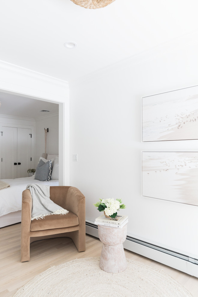 Diseño de dormitorio principal costero grande con paredes blancas, suelo de madera clara y suelo beige