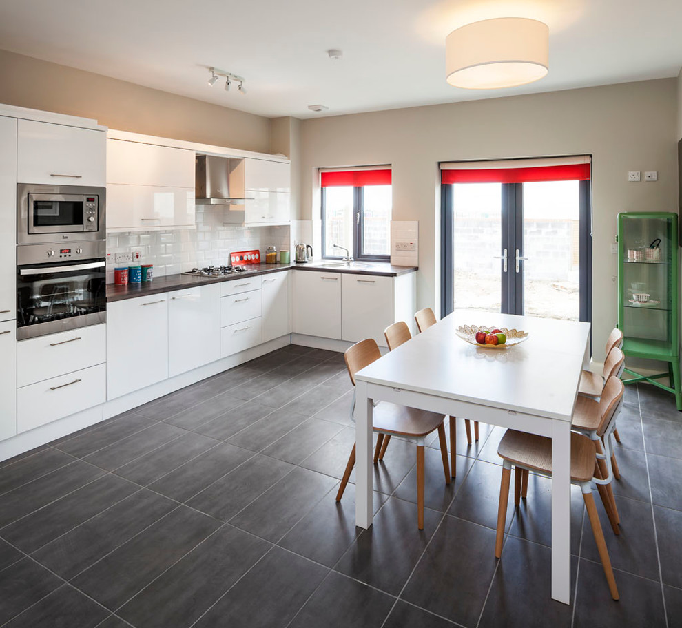 This is an example of a mid-sized contemporary l-shaped eat-in kitchen in Dublin with flat-panel cabinets, white cabinets, laminate benchtops, white splashback, subway tile splashback, stainless steel appliances, ceramic floors and no island.