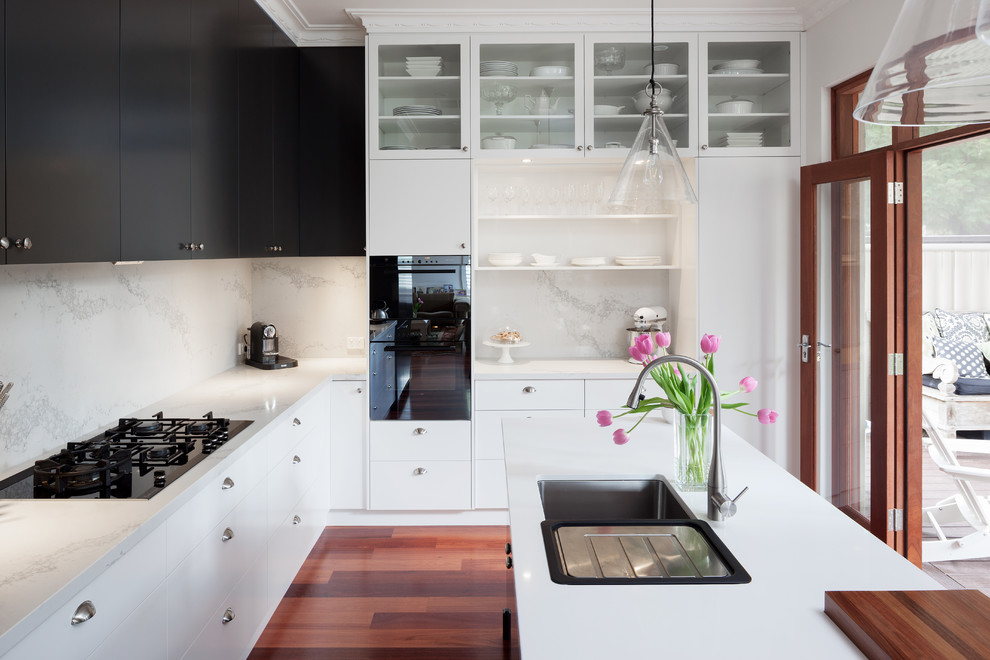 Inspiration for a contemporary kitchen in Perth with an undermount sink, flat-panel cabinets, white cabinets, quartz benchtops, white splashback, stone slab splashback, black appliances, with island and white benchtop.