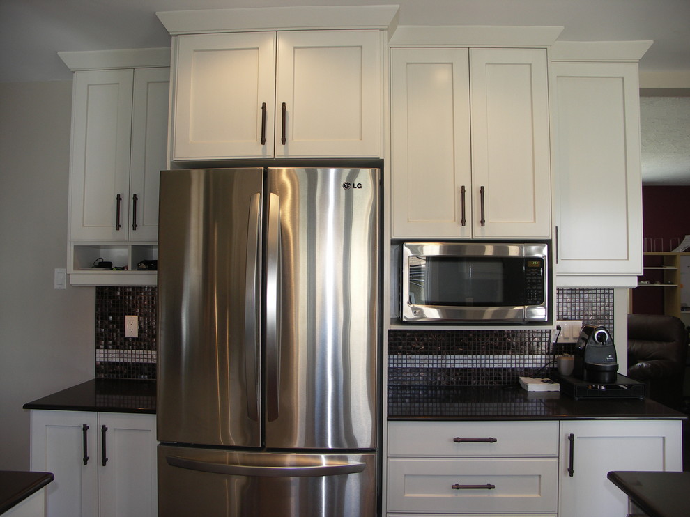 Kitchen - transitional u-shaped medium tone wood floor kitchen idea in Edmonton with an undermount sink, shaker cabinets, white cabinets, granite countertops, black backsplash and stainless steel appliances