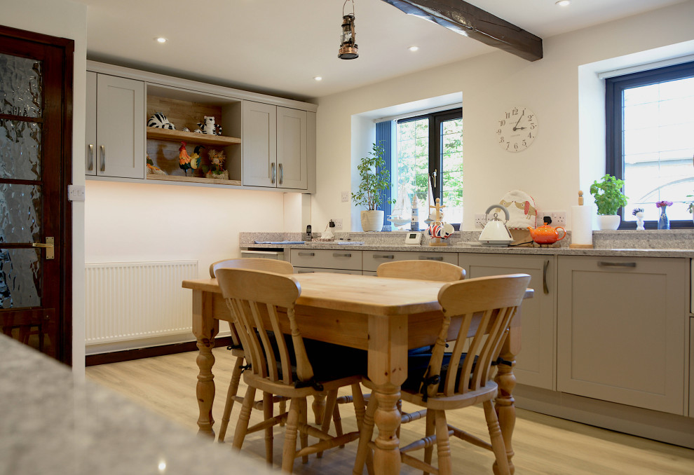 Photo of a large traditional eat-in kitchen in Cornwall with a farmhouse sink, shaker cabinets, grey cabinets and glass sheet splashback.