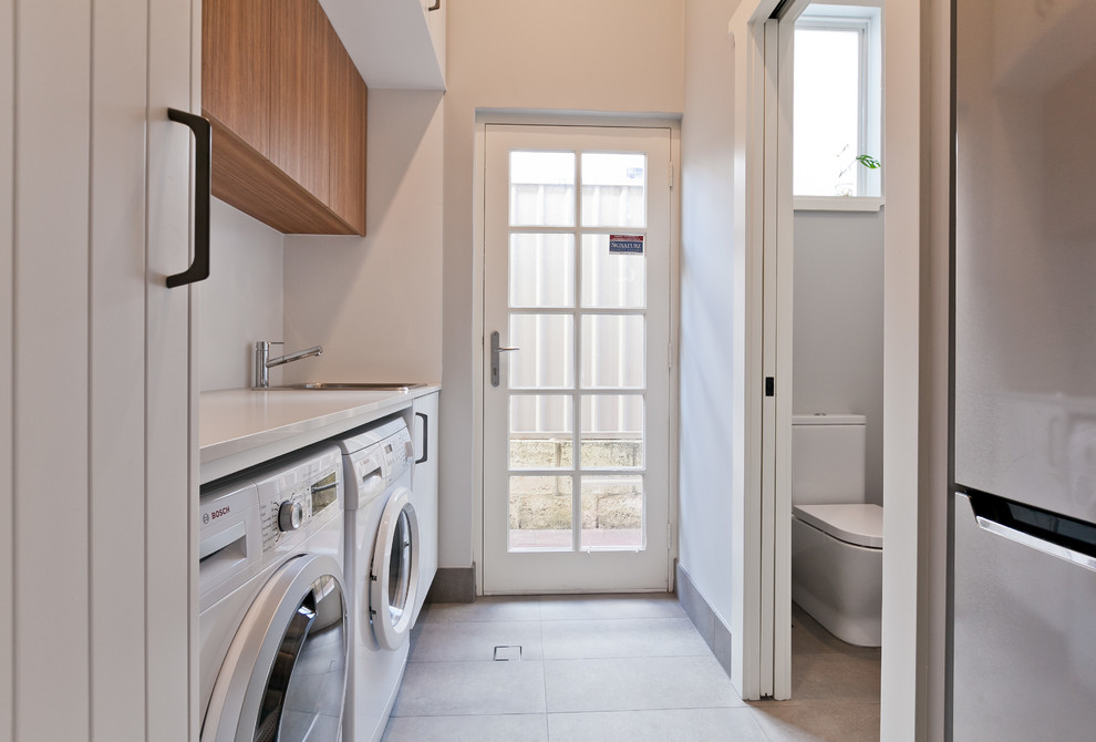 Design ideas for a small contemporary galley utility room in Perth with a drop-in sink, white cabinets, quartz benchtops, grey walls, porcelain floors, a side-by-side washer and dryer, grey floor and white benchtop.