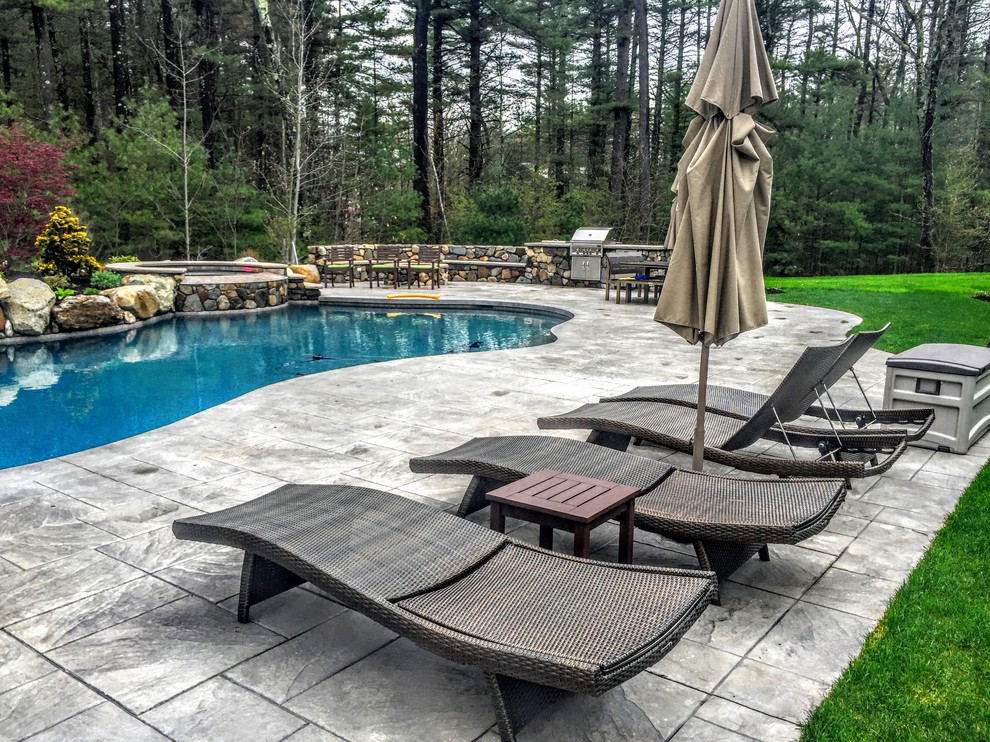 Inspiration for a mid-sized traditional backyard custom-shaped natural pool in Boston with a hot tub and stamped concrete.