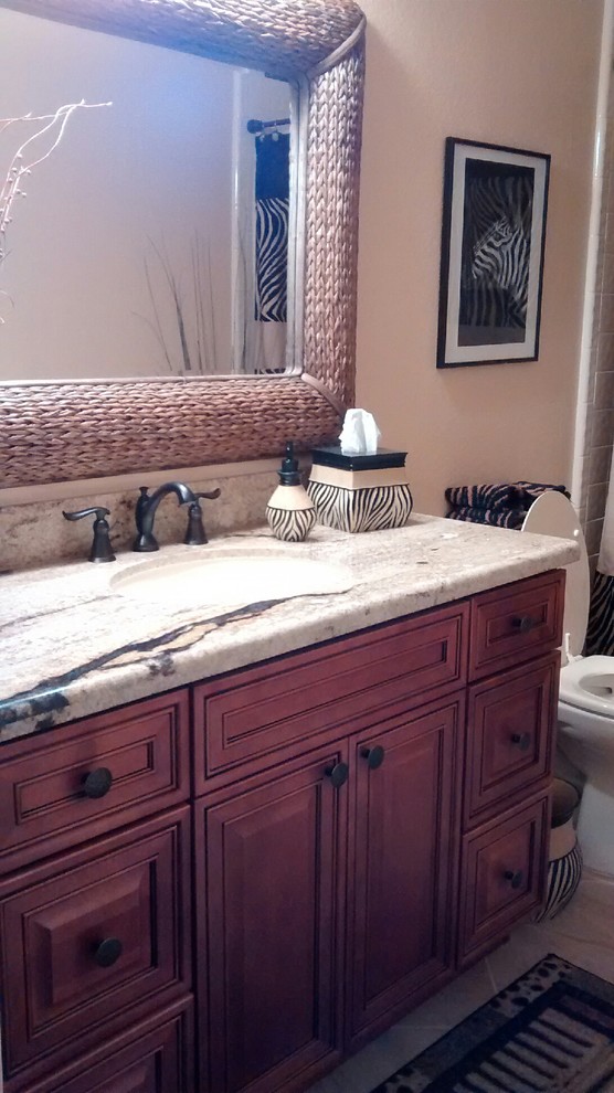 This is an example of a mid-sized transitional kids bathroom in Phoenix with raised-panel cabinets, medium wood cabinets, an alcove tub, a shower/bathtub combo, a two-piece toilet, beige tile, porcelain tile, beige walls, porcelain floors, an undermount sink and granite benchtops.