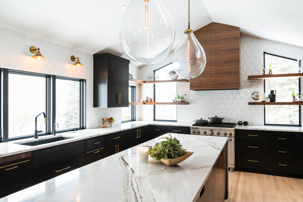 Foto på ett 50 tals flerfärgad kök, med en undermonterad diskho, släta luckor, svarta skåp, bänkskiva i kvarts, vitt stänkskydd, stänkskydd i keramik, rostfria vitvaror, ljust trägolv och en köksö