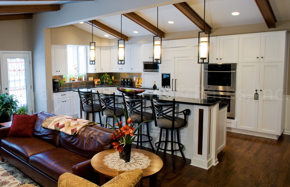 Inspiration for a traditional eat-in kitchen in Omaha with a single-bowl sink, shaker cabinets, white cabinets, granite benchtops, slate splashback, stainless steel appliances, medium hardwood floors, brown floor and black benchtop.