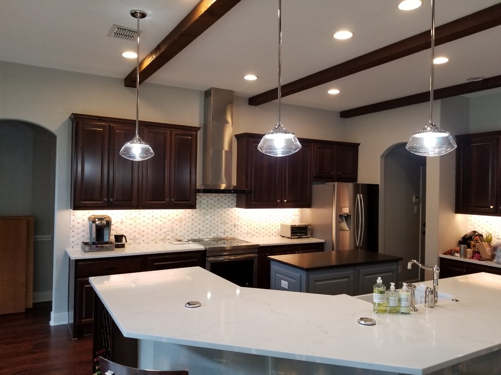 Inspiration for a mid-sized transitional u-shaped eat-in kitchen in Austin with a farmhouse sink, raised-panel cabinets, dark wood cabinets, quartz benchtops, white splashback, stone tile splashback, white appliances, dark hardwood floors, with island, brown floor and white benchtop.