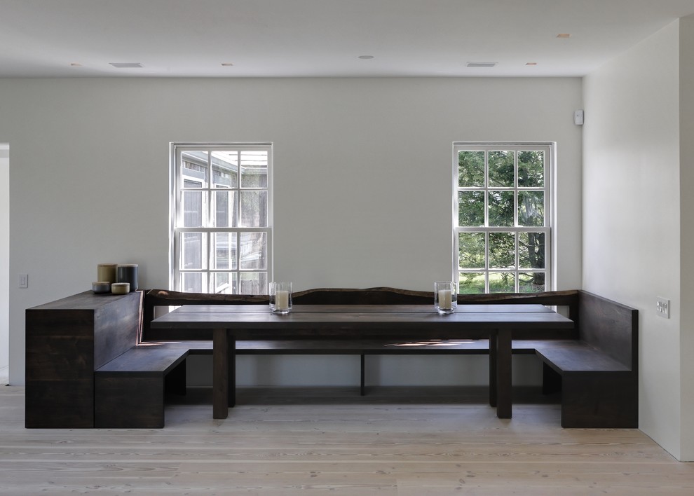 This is an example of a contemporary dining room in New York with white walls and medium hardwood floors.