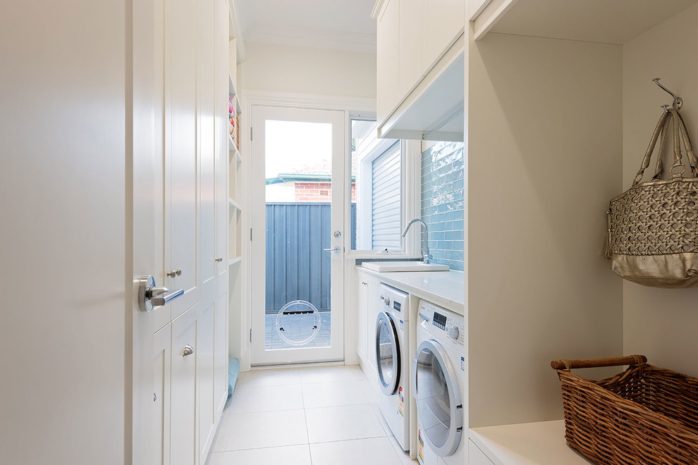 Mid-sized transitional galley dedicated laundry room in Adelaide with a drop-in sink, shaker cabinets, white cabinets, granite benchtops, white walls, ceramic floors, a side-by-side washer and dryer, white floor and white benchtop.
