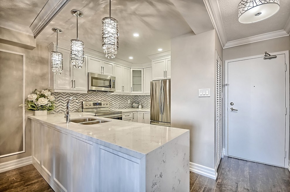 Open concept kitchen - mid-sized transitional u-shaped medium tone wood floor and brown floor open concept kitchen idea in Toronto with an undermount sink, recessed-panel cabinets, white cabinets, quartz countertops, gray backsplash, marble backsplash, stainless steel appliances and a peninsula