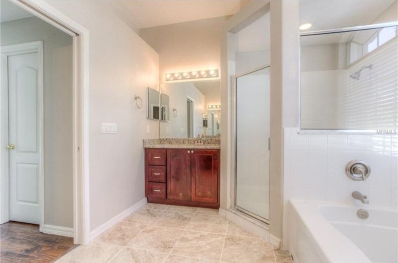 Inspiration for a mid-sized traditional master bathroom in San Diego with recessed-panel cabinets, dark wood cabinets, granite benchtops, multi-coloured benchtops, an alcove tub, a corner shower, ceramic tile, grey walls, ceramic floors, an undermount sink, beige floor and a hinged shower door.
