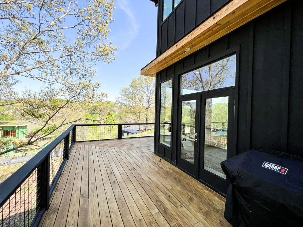 Photo of a mid-sized modern backyard and first floor deck in Other with an awning and metal railing.