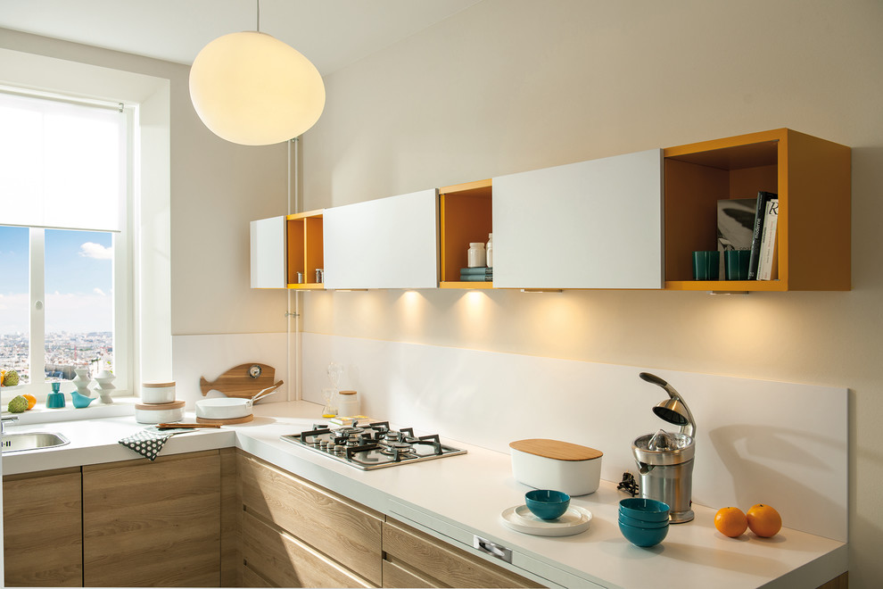 This is an example of a small contemporary l-shaped kitchen in London with a single-bowl sink, white splashback, glass sheet splashback, stainless steel appliances, light wood cabinets and ceramic floors.