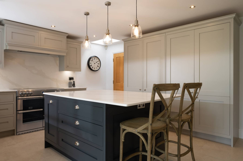 Large traditional u-shaped open plan kitchen in Hertfordshire with a built-in sink, shaker cabinets, grey cabinets, quartz worktops, white splashback, stainless steel appliances, an island and white worktops.