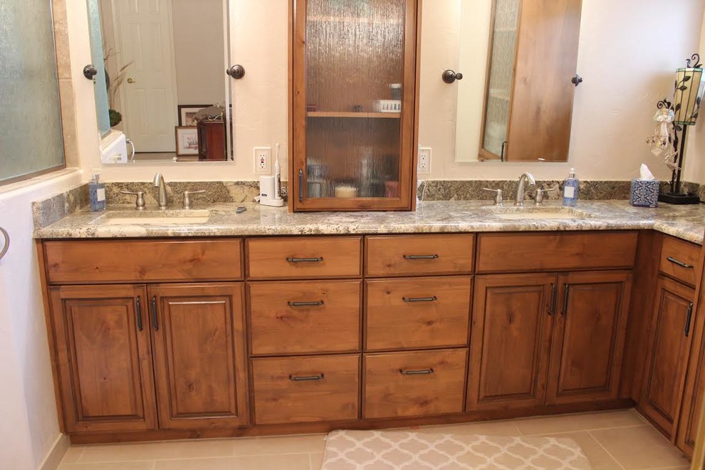 This is an example of a mid-sized traditional master bathroom in Phoenix with raised-panel cabinets, medium wood cabinets, an alcove shower, brown tile, porcelain tile, beige walls, porcelain floors, an undermount sink, granite benchtops, beige floor and an open shower.