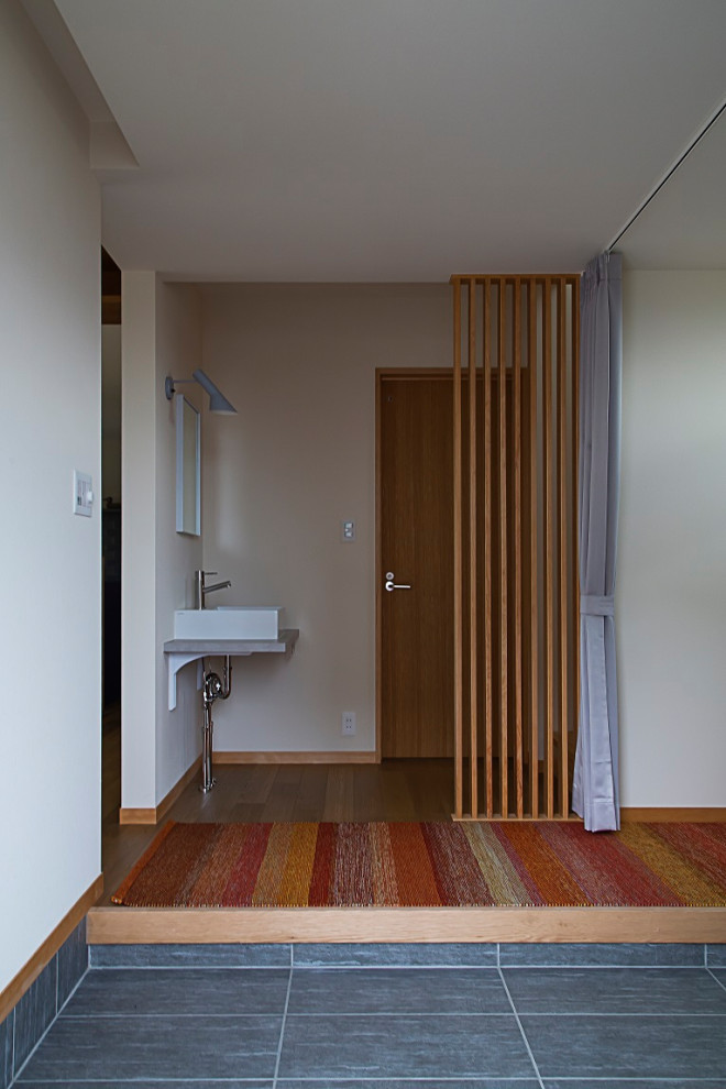 На фото: узкая прихожая среднего размера в скандинавском стиле с полом из керамической плитки, одностворчатой входной дверью, металлической входной дверью, серым полом, потолком с обоями и обоями на стенах