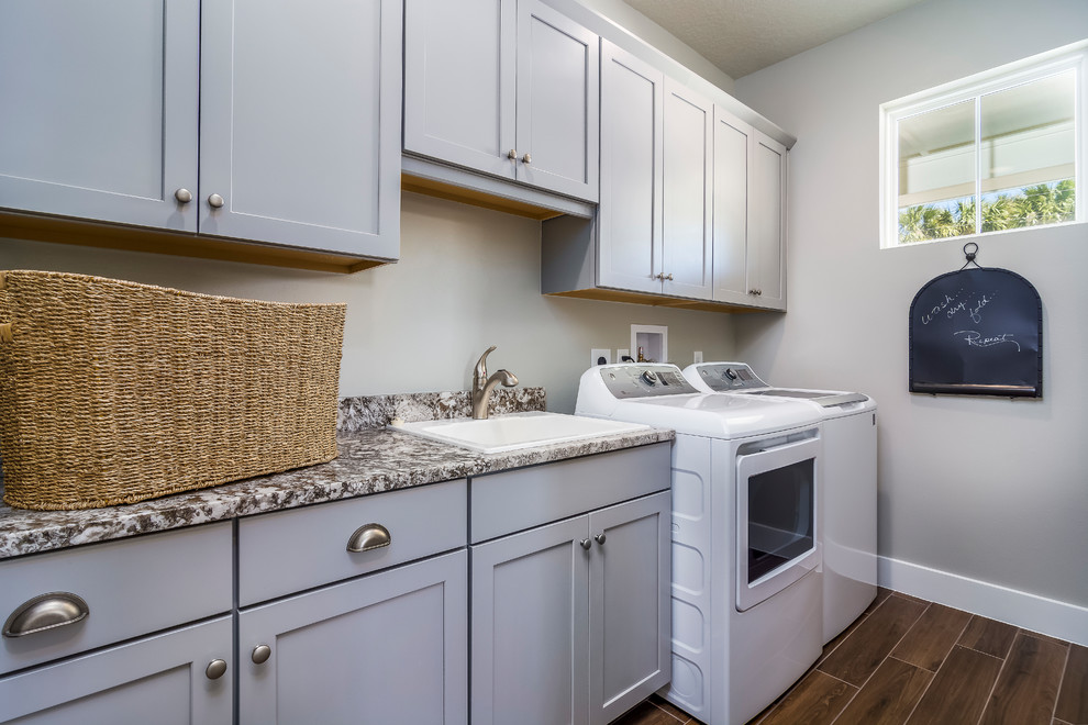 Mid-sized transitional galley dedicated laundry room in Other with a drop-in sink, shaker cabinets, grey cabinets, laminate benchtops and grey walls.