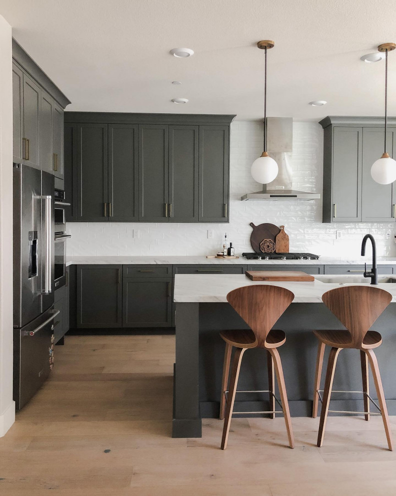 Inspiration for a transitional l-shaped open plan kitchen in San Francisco with an undermount sink, shaker cabinets, grey cabinets, marble benchtops, white splashback, ceramic splashback, stainless steel appliances, light hardwood floors, with island, brown floor and white benchtop.