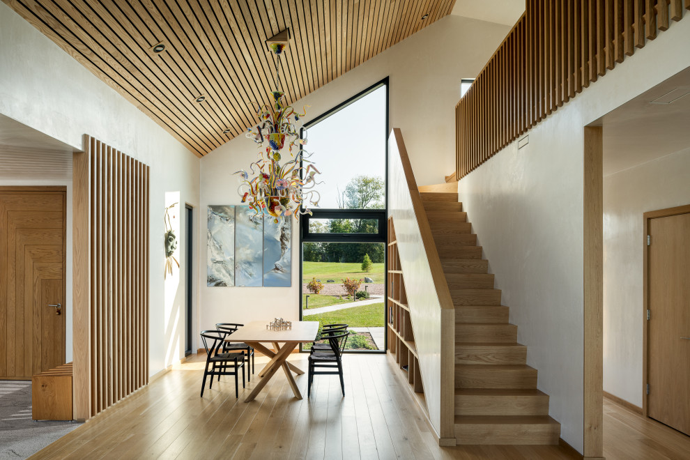 Foto di una grande sala da pranzo aperta verso il soggiorno minimal con pareti beige, parquet chiaro, soffitto in legno e pareti in legno