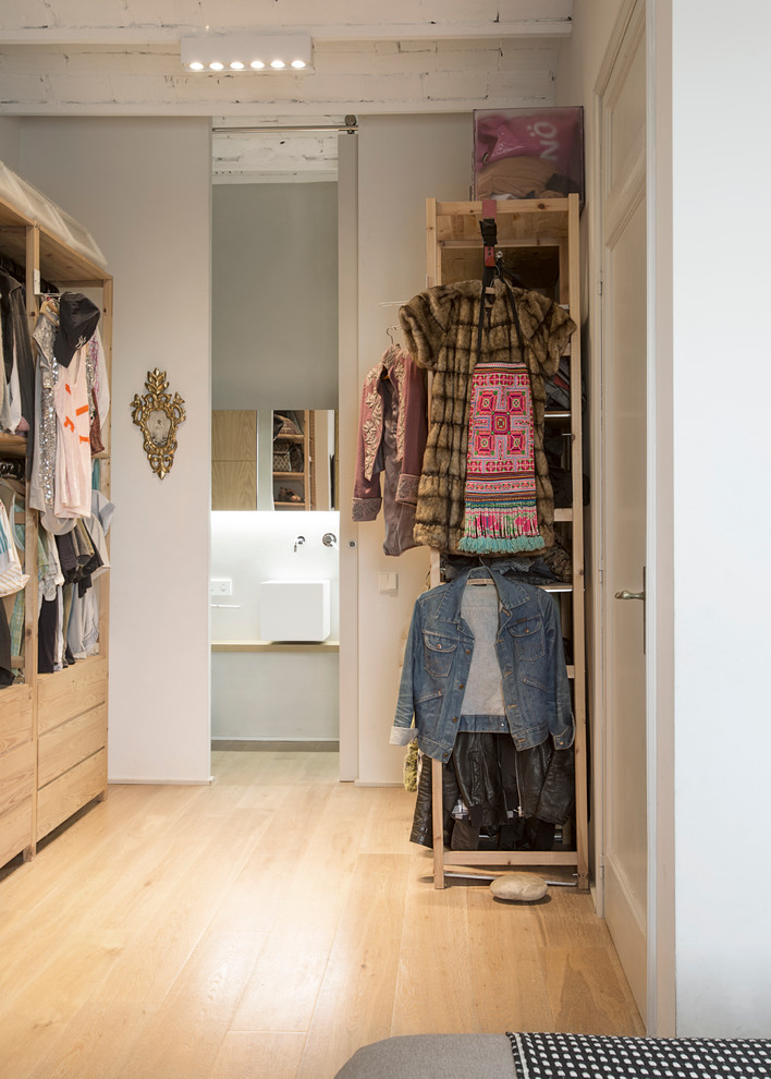 Design ideas for a mid-sized contemporary gender-neutral dressing room in Barcelona with open cabinets, medium wood cabinets and medium hardwood floors.