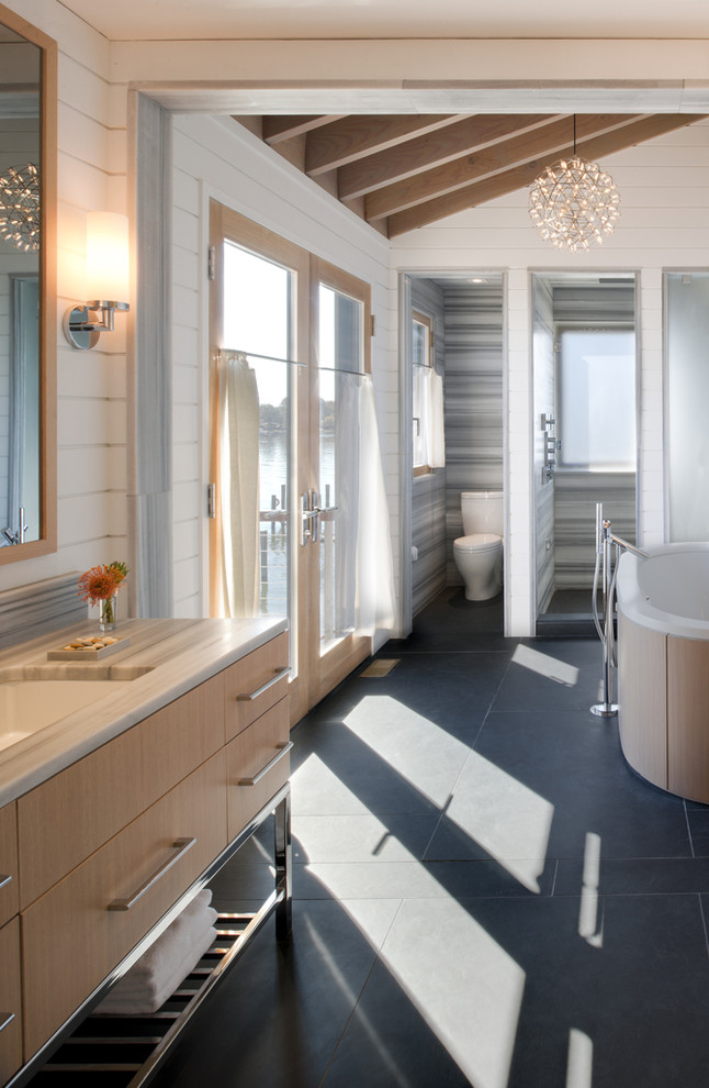 Photo of a contemporary bathroom in DC Metro with an undermount sink, flat-panel cabinets, light wood cabinets, a freestanding tub, an alcove shower and white walls.
