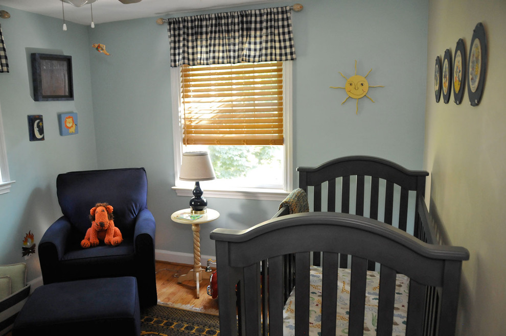 Photo of a mid-sized transitional nursery for boys with blue walls and light hardwood floors.