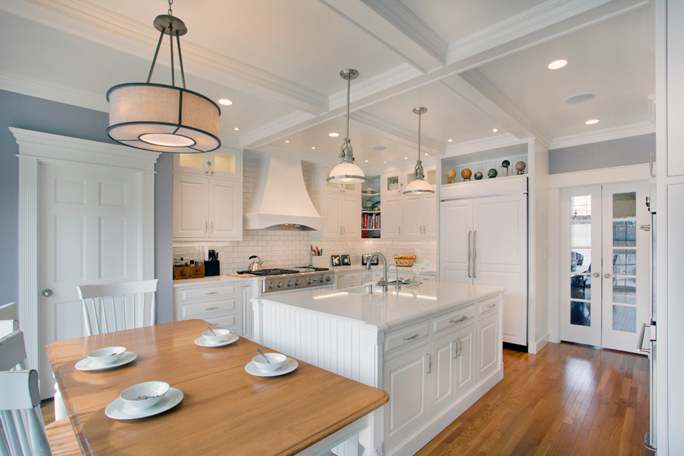 Inspiration for a large transitional l-shaped medium tone wood floor eat-in kitchen remodel with a farmhouse sink, white cabinets, granite countertops, white backsplash, stainless steel appliances, an island, raised-panel cabinets and subway tile backsplash