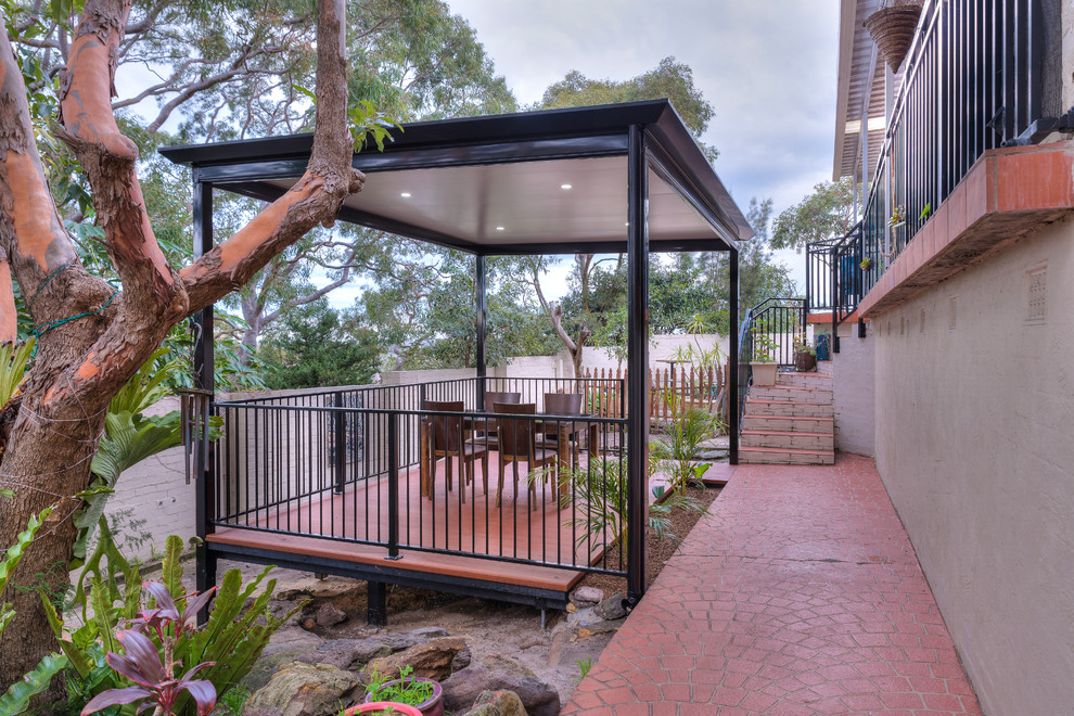 This is an example of a mid-sized modern backyard patio in Sydney with decking and a pergola.
