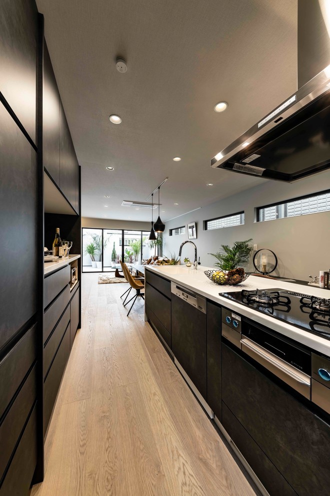 Mid-sized contemporary single-wall separate kitchen in Other with an integrated sink, black cabinets, recycled glass benchtops, brown splashback, panelled appliances, plywood floors, with island, grey floor, white benchtop and flat-panel cabinets.