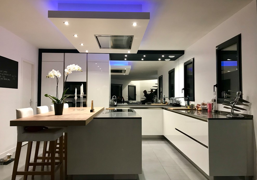 Large contemporary l-shaped separate kitchen in Paris with black appliances, porcelain floors, with island and grey floor.