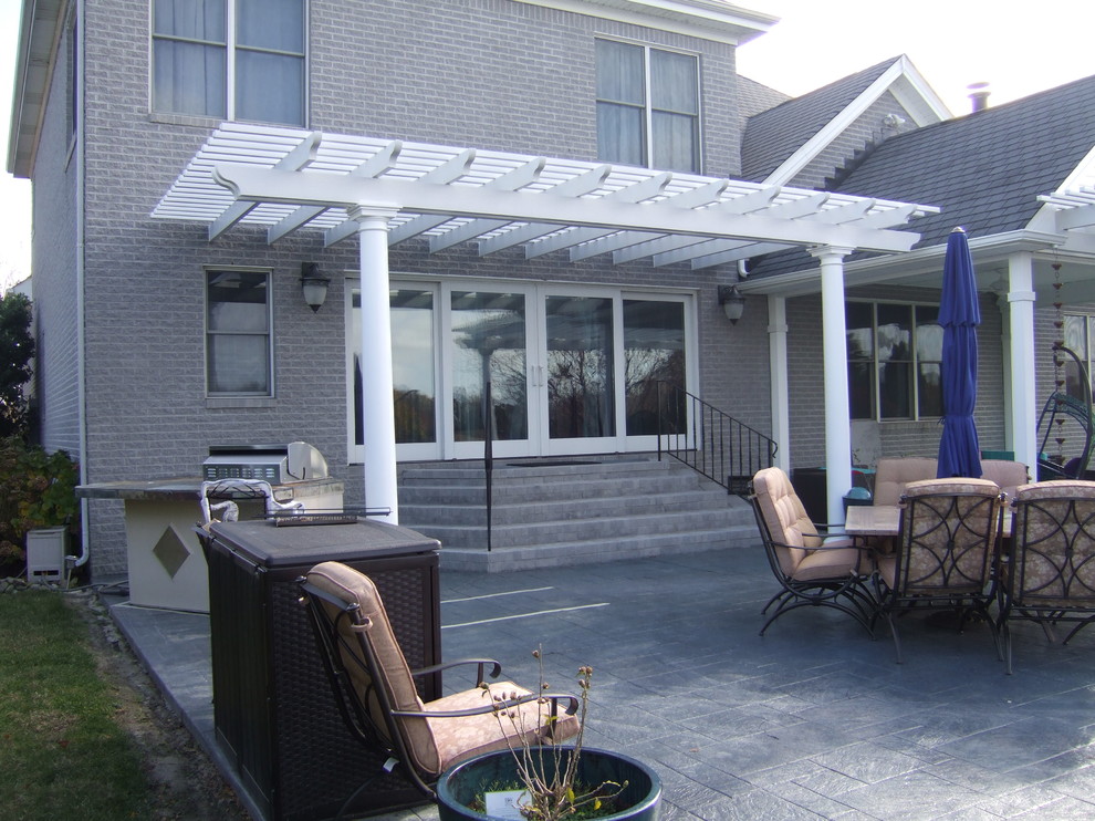 Inspiration for a large traditional backyard patio in Other with a pergola and concrete pavers.