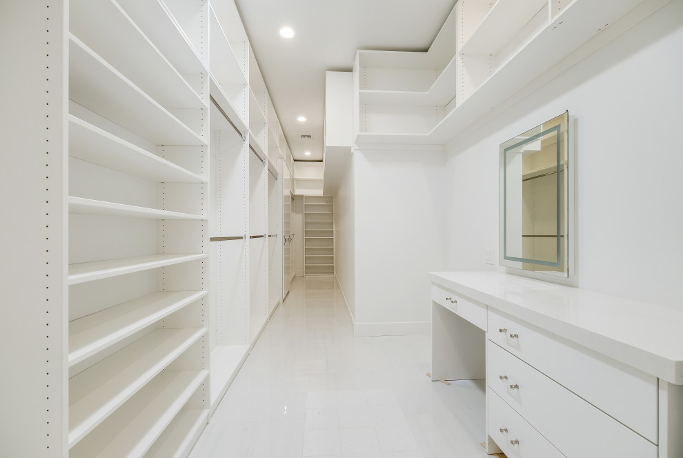 Large modern gender-neutral walk-in wardrobe in Phoenix with flat-panel cabinets, white cabinets, ceramic floors and white floor.